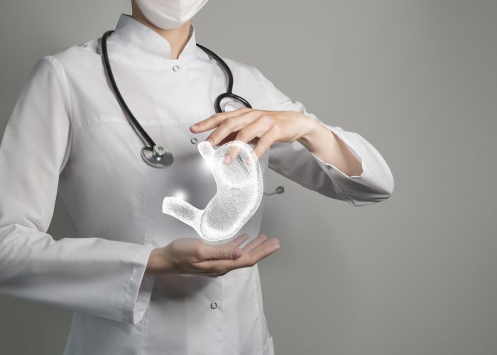 Female doctor holding virtual Stomach in hand. Handrawn human organ, copy space on right side, raw photo colors. Healthcare hospital service concept stock photo